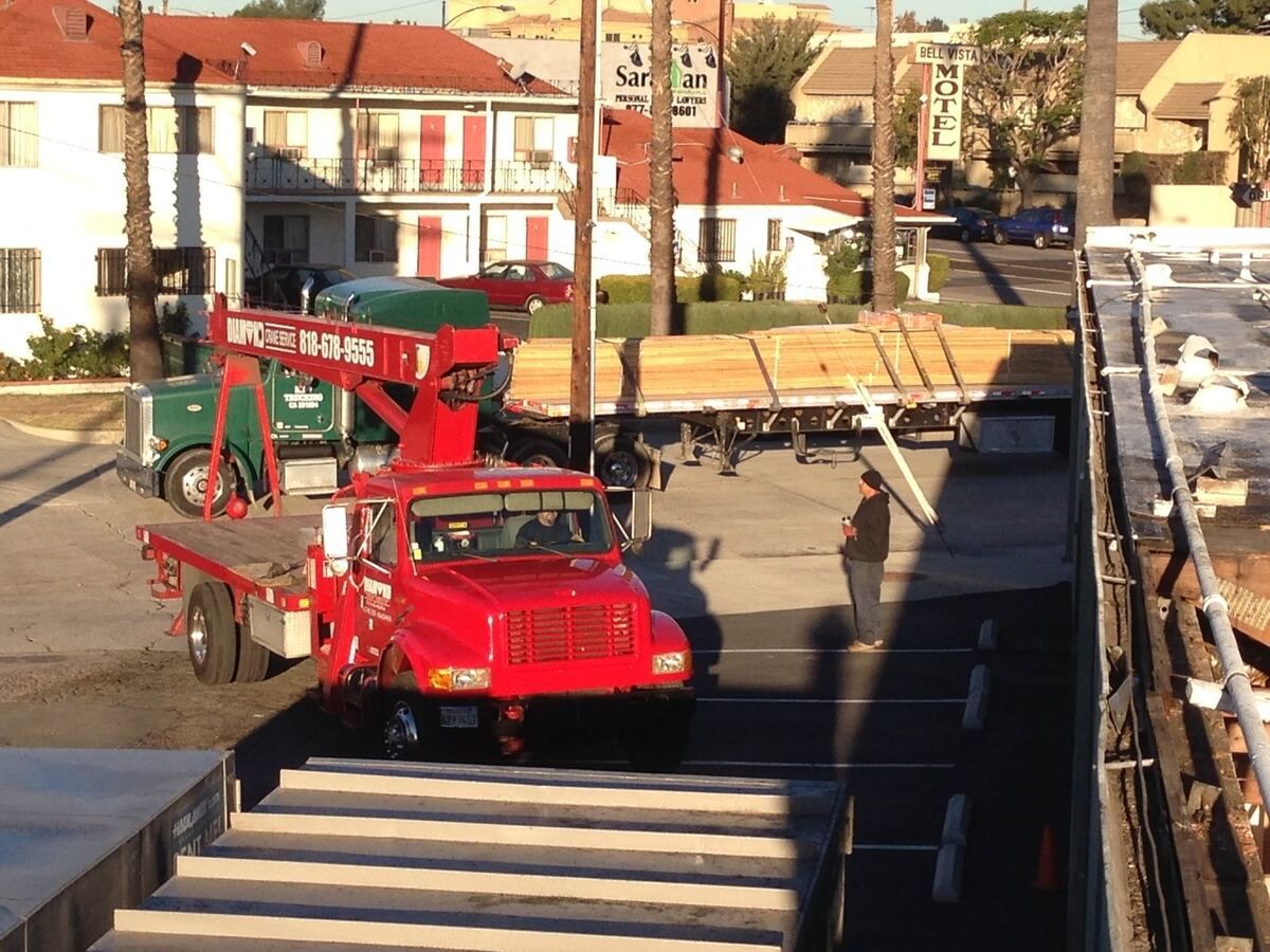 Boom truck lifting roof material onto the Burbank plaza from the street